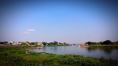 Built structure by river against clear blue sky