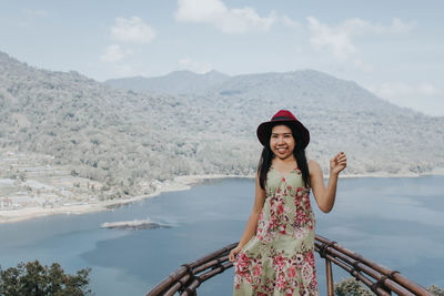 Portrait of young woman standing against mountain