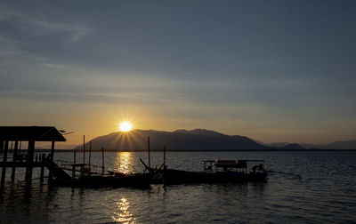 Silhouette boats in sea against sky during sunset