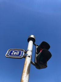 Low angle view of telephone pole against clear blue sky