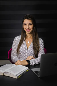 Portrait of a smiling young woman sitting on table