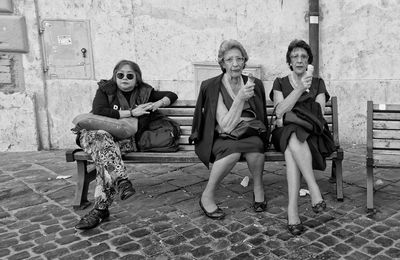 Full length portrait of friends sitting in city