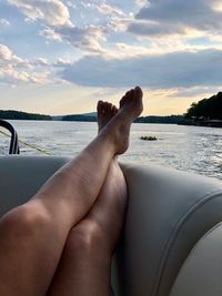 Low section of person relaxing on sea against sky