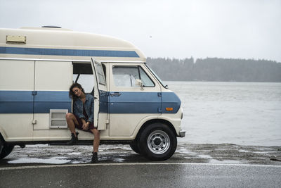 Teenage girl getting into vintage van on rainy day