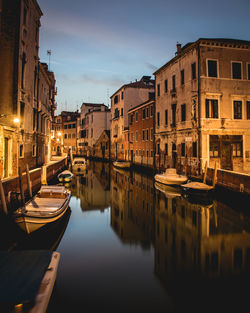 Boats moored in canal amidst buildings in city