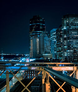 Illuminated cityscape against clear blue sky at night