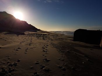 Sand dunes at beach against sky