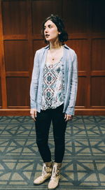 Full length of a beautiful young woman standing against tiled floor
