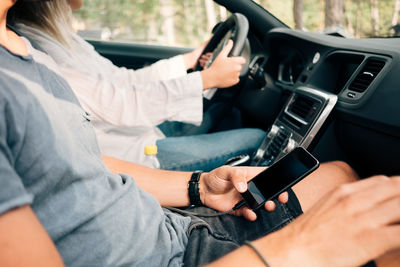Midsection of man using mobile phone while sitting in car