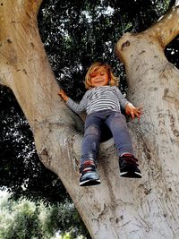 Full length of cute boy on tree trunk