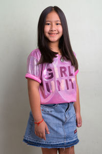 Portrait of smiling girl standing against wall