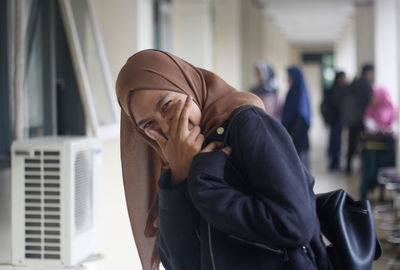 Portrait of woman gesturing while standing in corridor