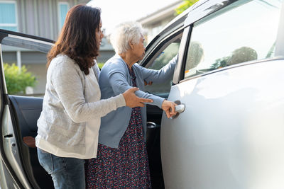 Caregiver help asian senior or elderly old lady woman patient get to her car, 