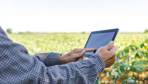 Midsection of man using mobile phone on field