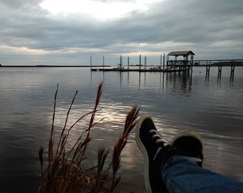 Low section of person on sea against sky