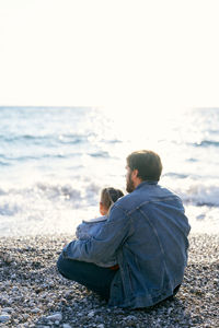 Rear view of couple sitting on beach