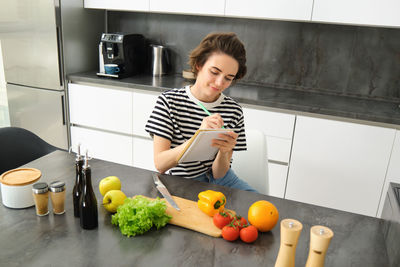 Portrait of young woman holding food at home