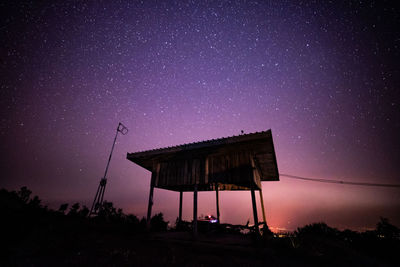 Low angle view of silhouette built structure against star field sky at night