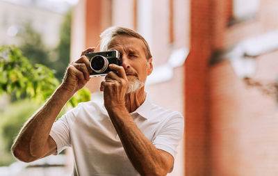 Portrait of man holding camera outdoors