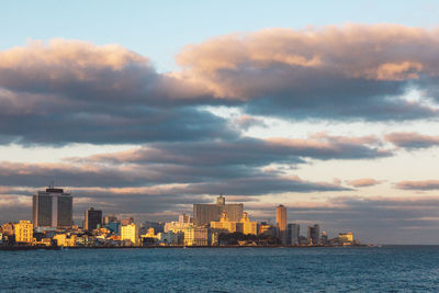 Sea by buildings against sky in city