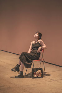 Side view of woman sitting on sand against clear sky