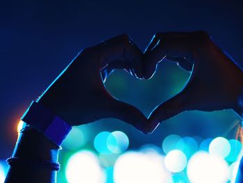 Close-up of heart shape against illuminated blue lights