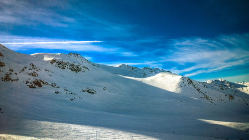 Scenic view of snowcapped mountains against blue sky