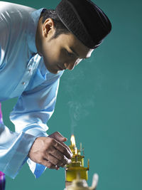 Man burning oil lamps against green background