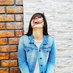 Young woman smiling against brick wall