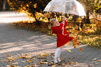 Woman with umbrella on footpath during autumn