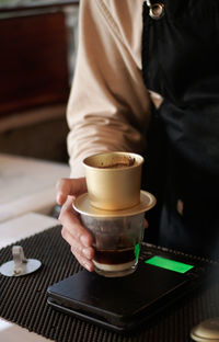 Midsection of man holding coffee on table