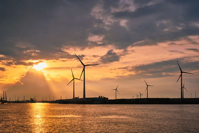 Wind turbines in antwerp port on sunset.
