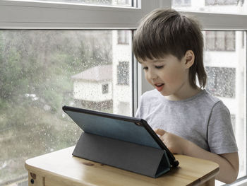 Curious boy watch cartoons on digital tablet. kid uses electronic device. indoor leisure for child..