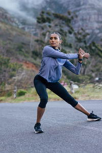 Full length of woman exercising on road