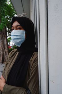 Portrait of woman standing against door