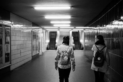 Rear view of people walking on illuminated corridor