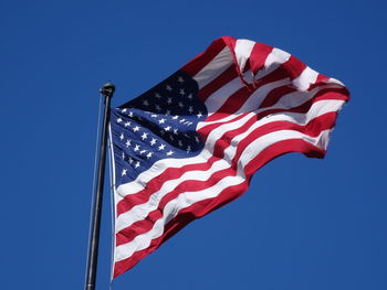 Low angle view of american flag against clear blue sky