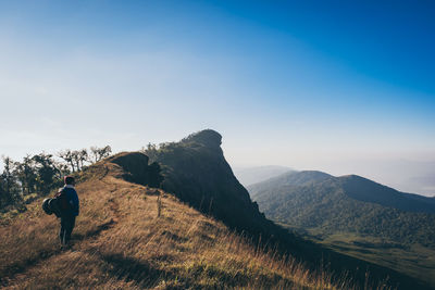 Male hiker standing on mountain against clear blue sky