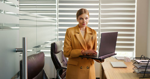 Portrait of business woman with a laptop in her hand in office. 