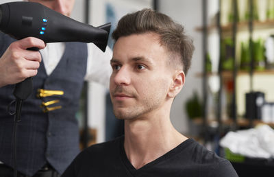 Hairdresser drying hair of male customer in salon