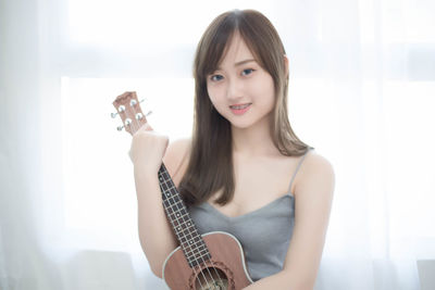 Portrait of young woman with guitar at home