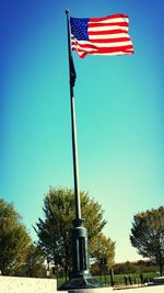 Low angle view of american flag against clear blue sky