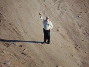 High angle portrait of senior man with walking cane standing on field