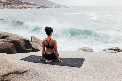 Rear view of woman sitting on beach