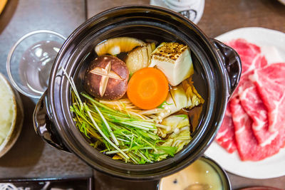 A bowl of hot japanese soup with various vegetables and meat