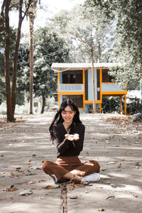 Portrait of smiling woman sitting against trees
