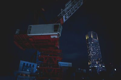 Low angle view of crane against sky in city at night