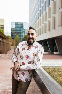 Bearded man standing and relaxing on stairs against office building