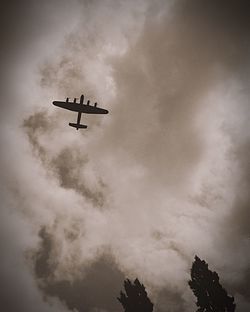 Low angle view of airplane in flight against clouds