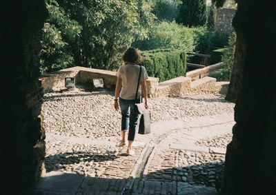 Rear view of woman walking on footpath